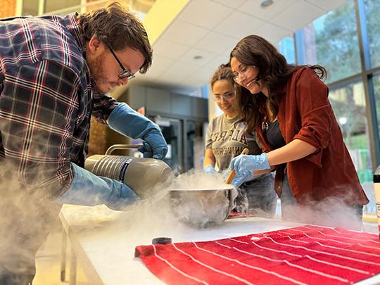 two students, professor conduct experiment